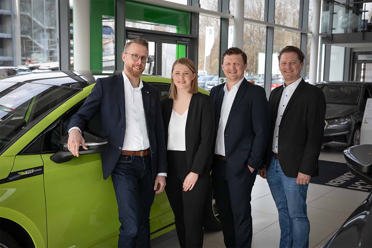 Die Geschäftsführung steht vor einem grünen Auto